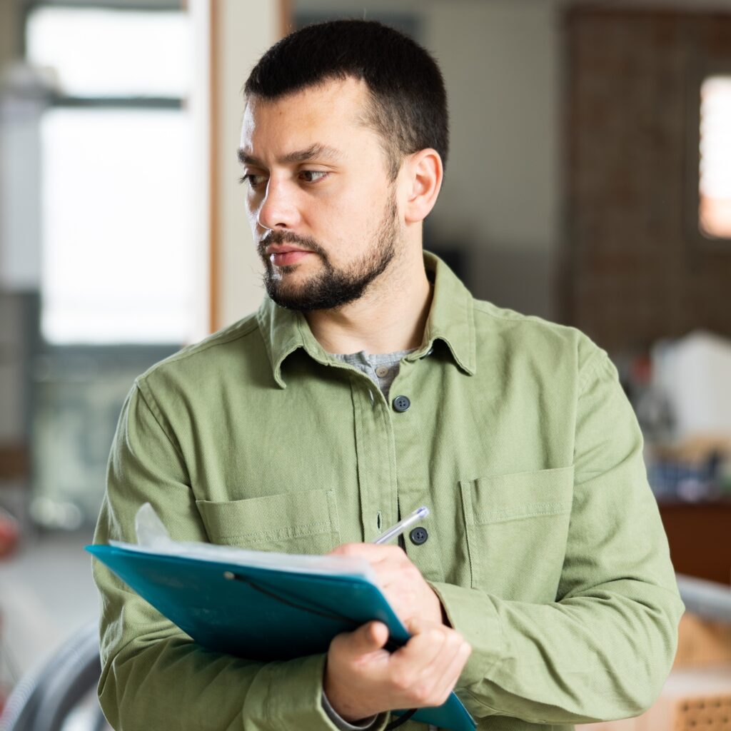 Restoration or remediation professional writes on clipboard while investigating customer complaints onsite.
